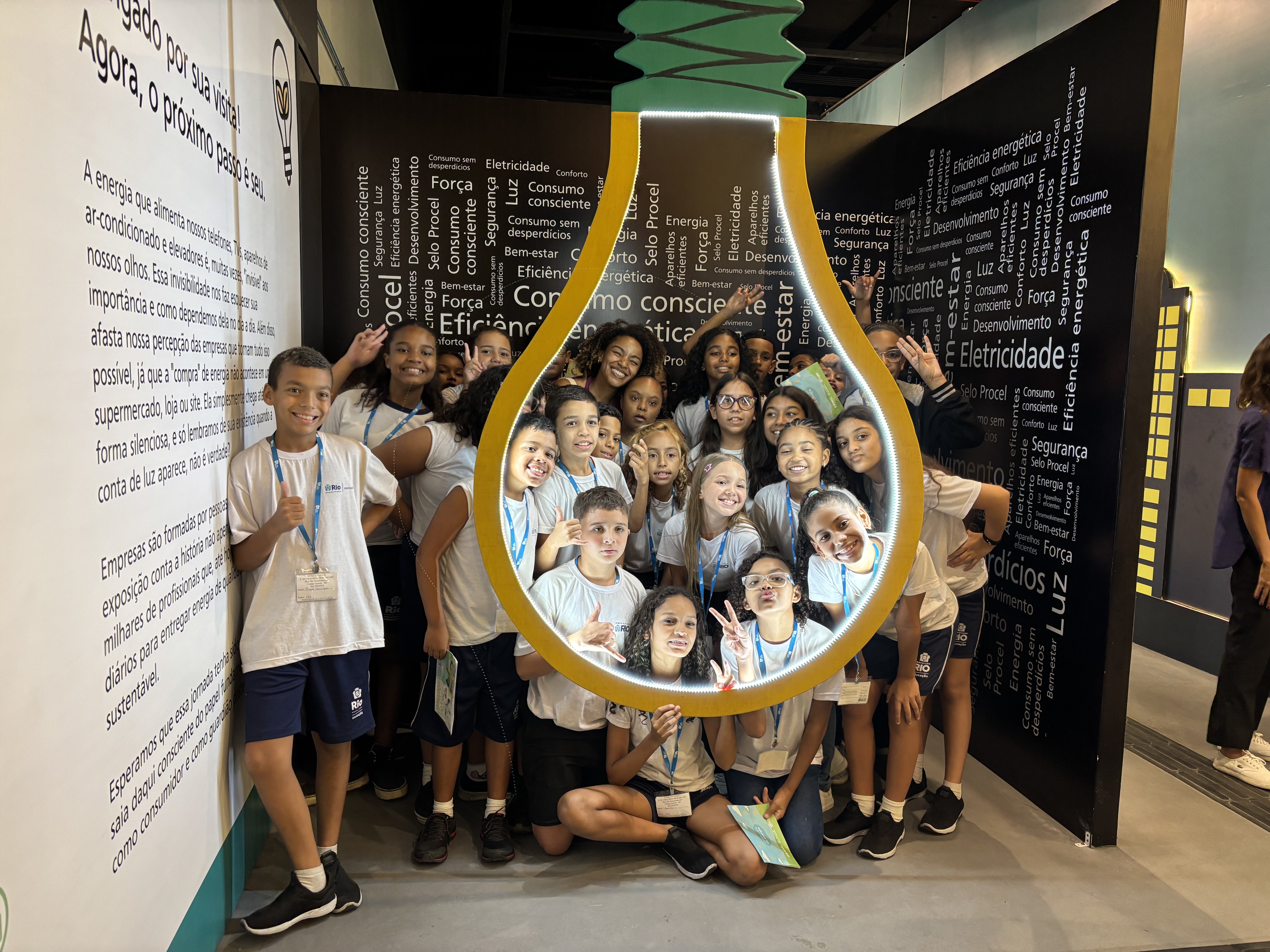Grupo de estudantes posando dentro da escultura de lâmpada na exposição